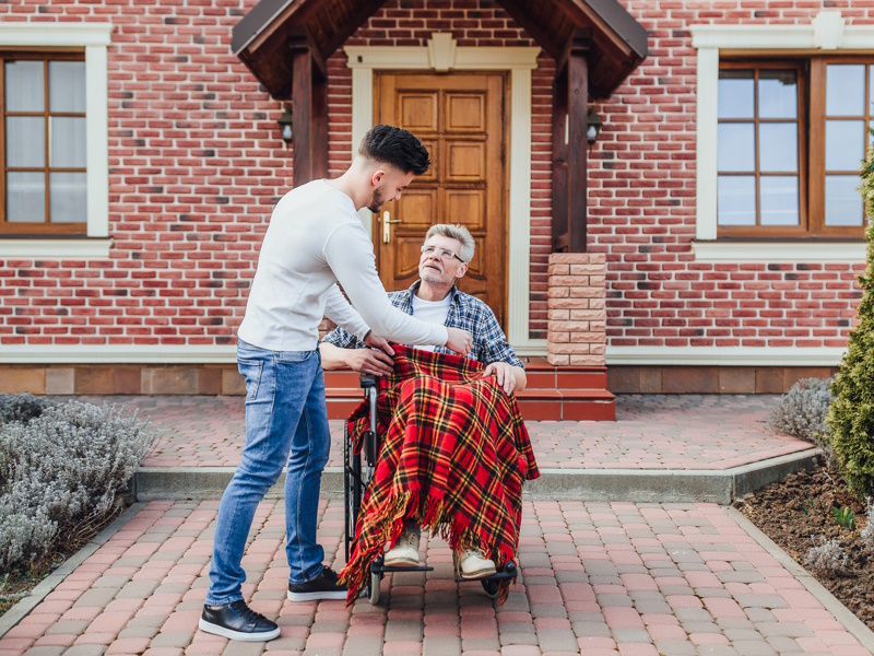 son-helping-his-father-wheelchair-near-nursing-home